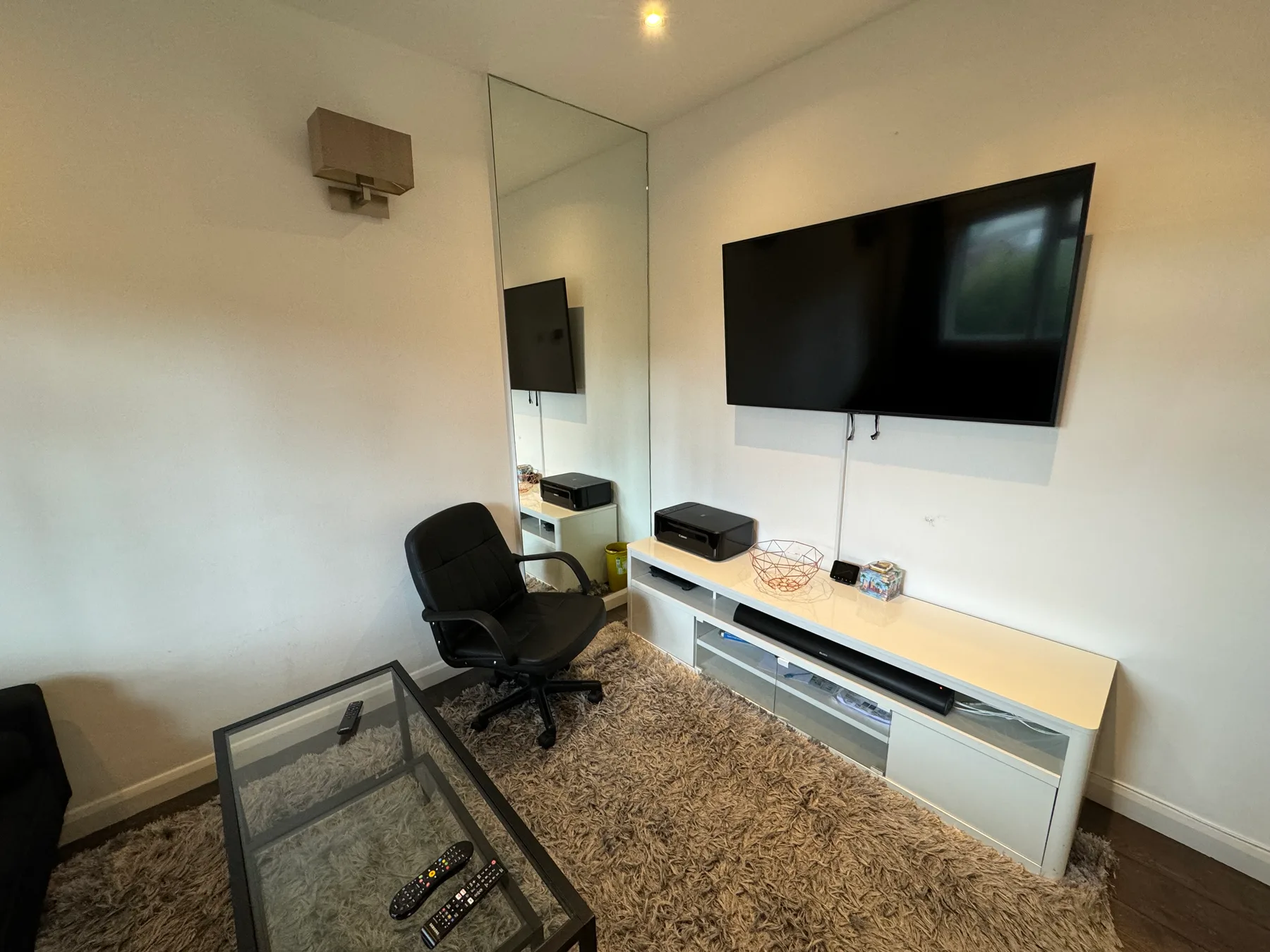 A room with a wall-mounted television, a desk, and a chair.