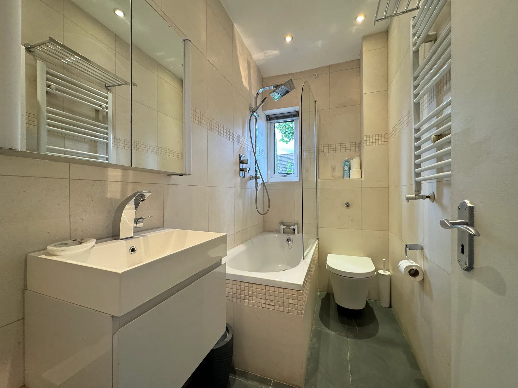 A tiled bathroom with a sink, bathtub, and toilet.