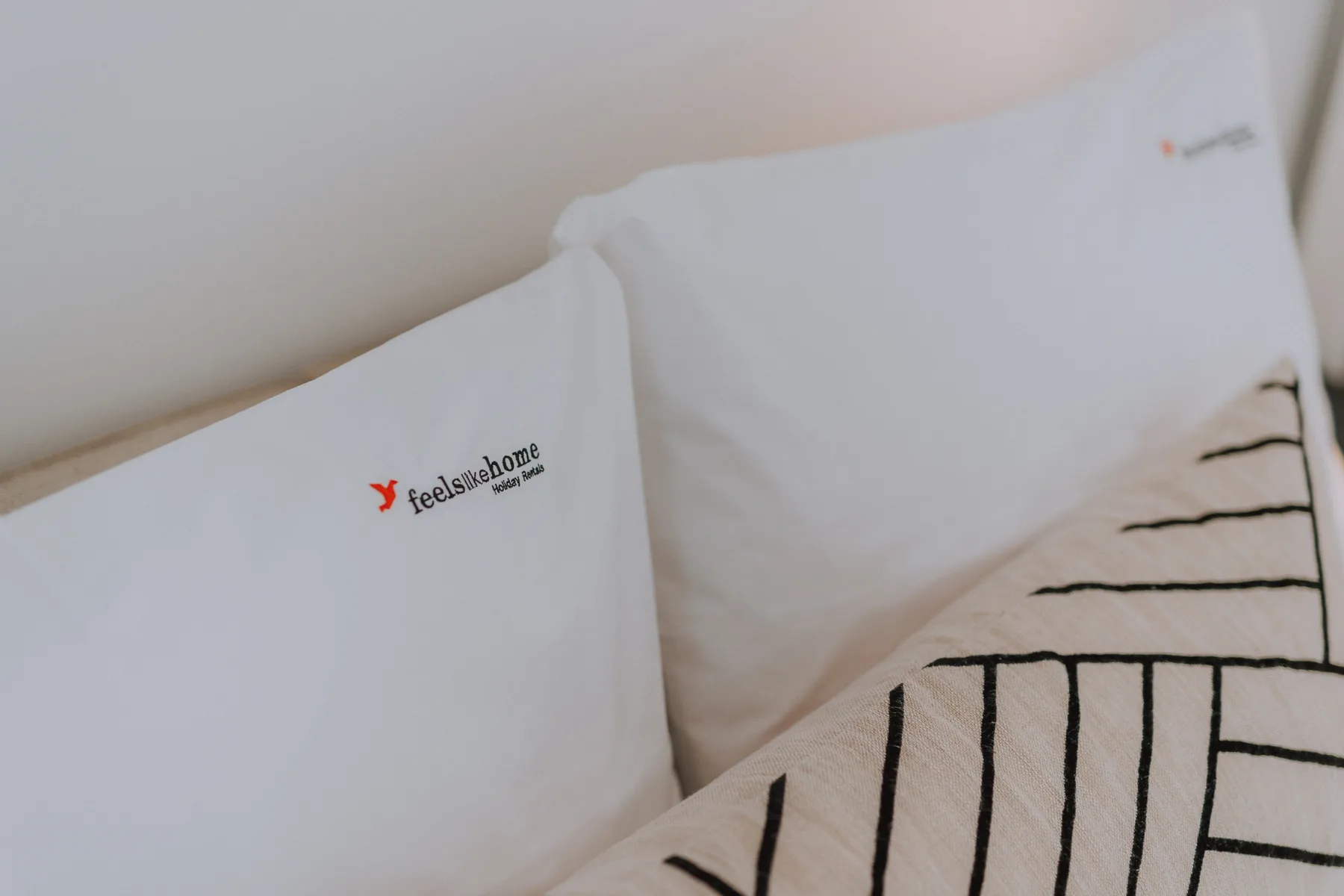 Almohadas de dormitorio con una funda blanca y un cojín de líneas negras.