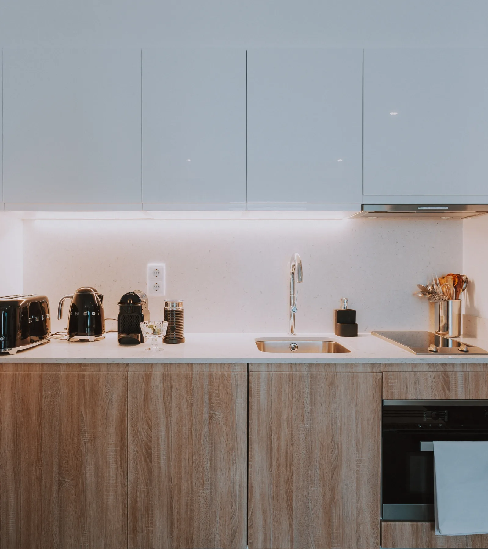 Una cocina moderna con fregadero, pequeños electrodomésticos y armarios de acabado madera.