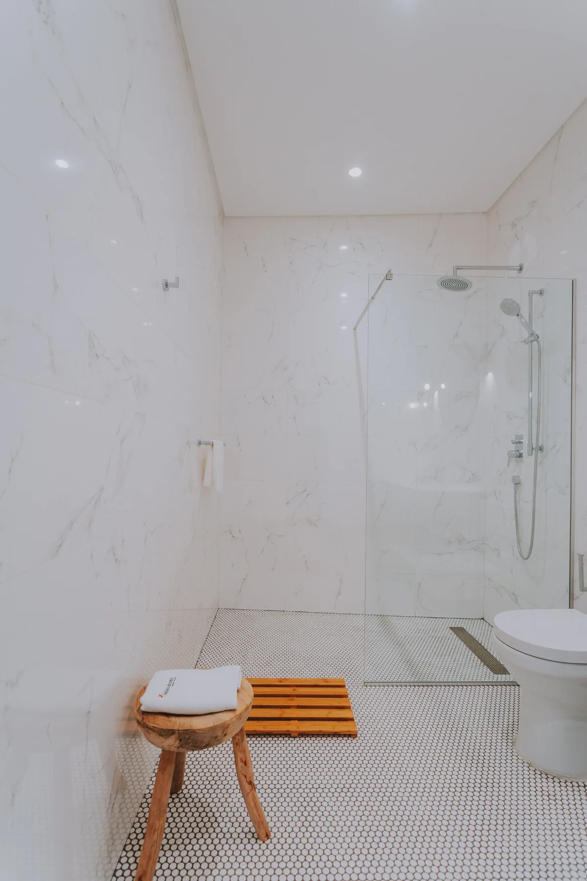 Un baño luminoso con una ducha de vidrio y un lavabo blanco.