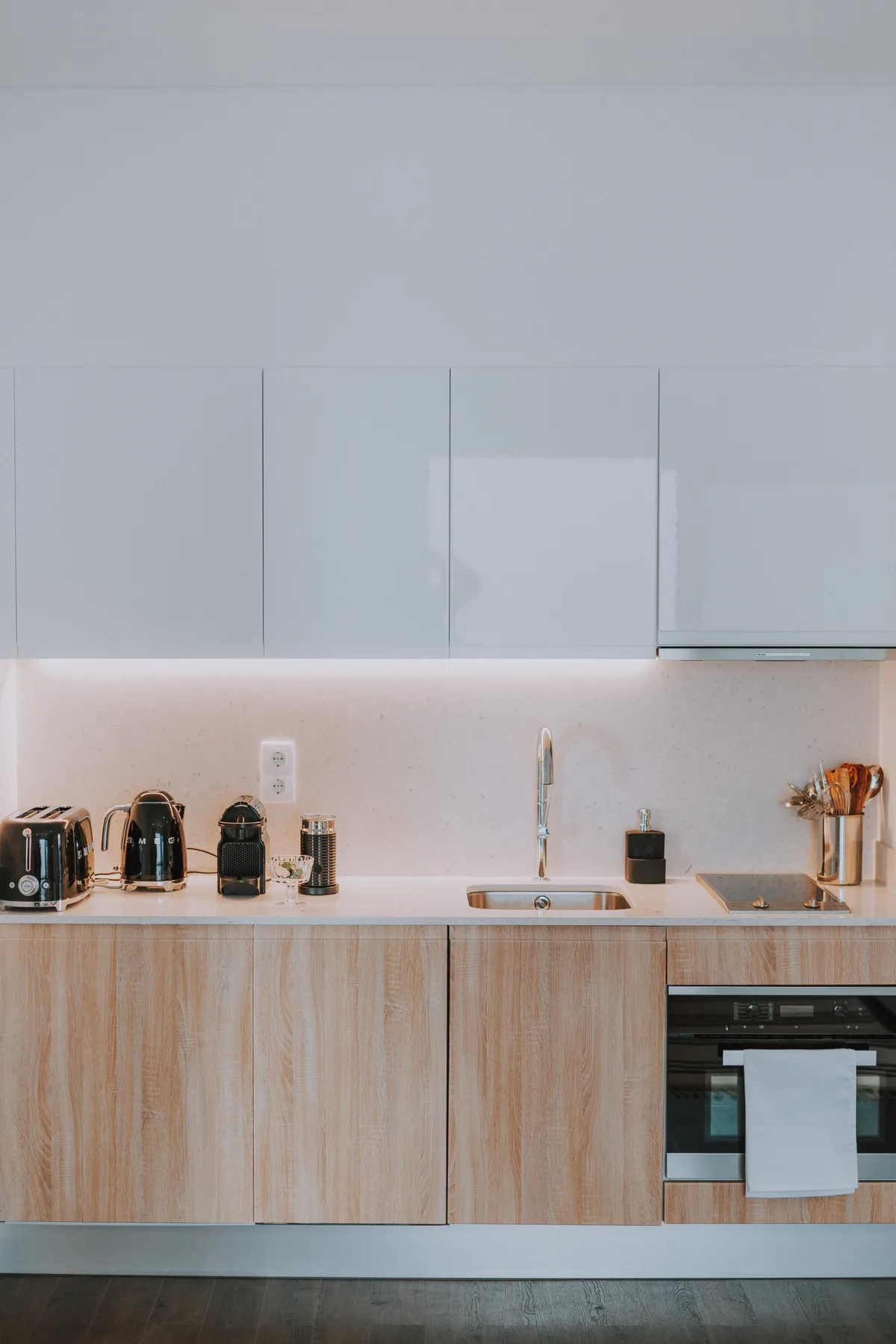Cocina moderna con armarios de madera clara y un horno integrado.