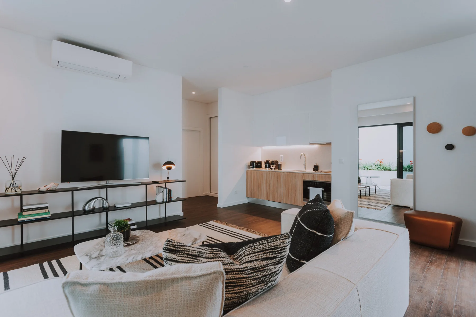 Una sala luminosa con televisor y una cocina abierta.