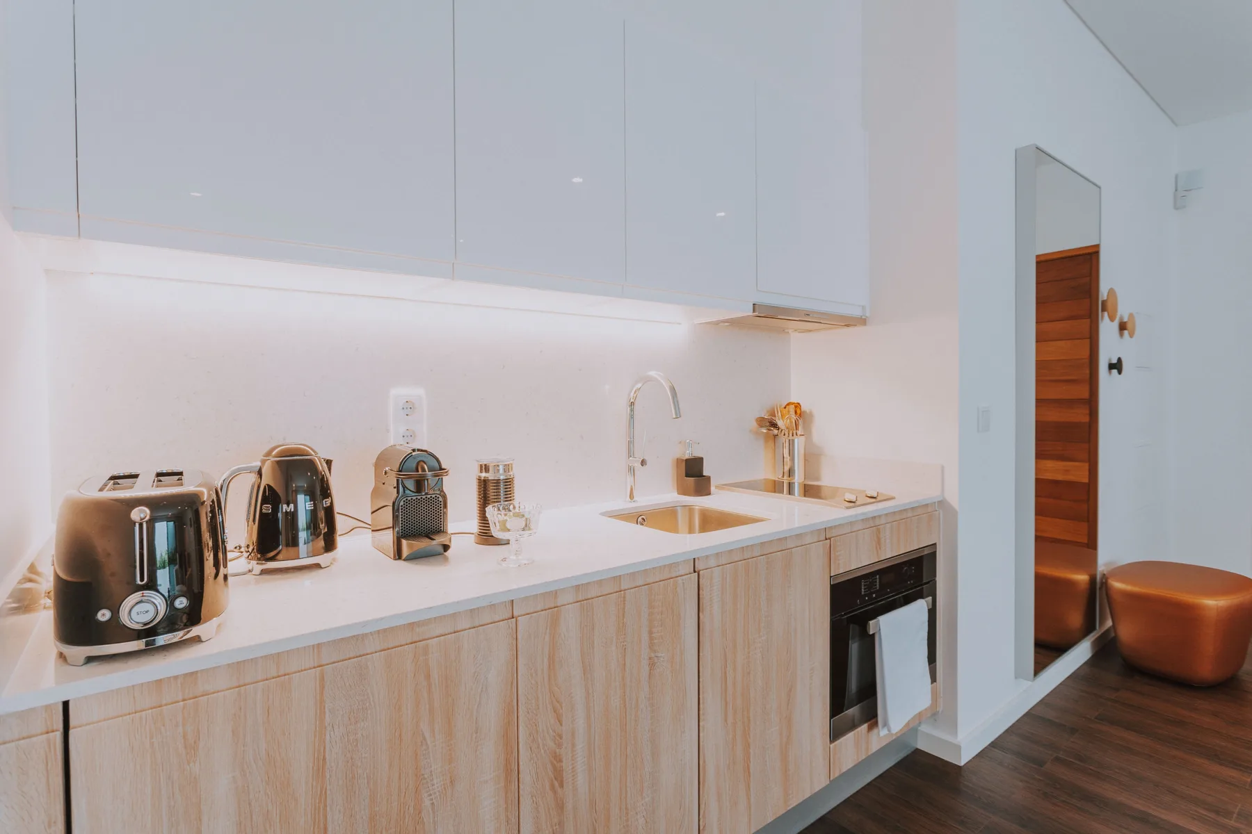 Una cocina moderna con pequeños electrodomésticos y un horno empotrado.