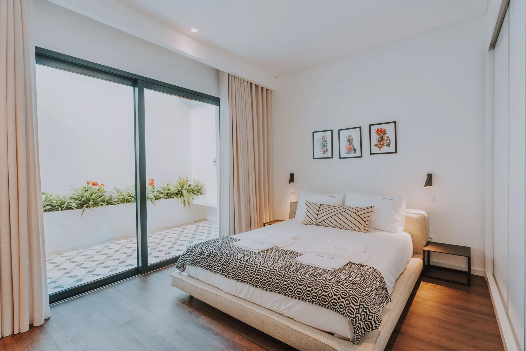 Un dormitorio luminoso con una cama junto a puertas corredizas de vidrio que dan a un balcón.
