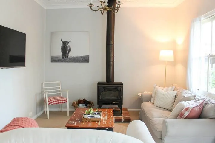 Una sala luminosa con un sofá y una estufa de leña.