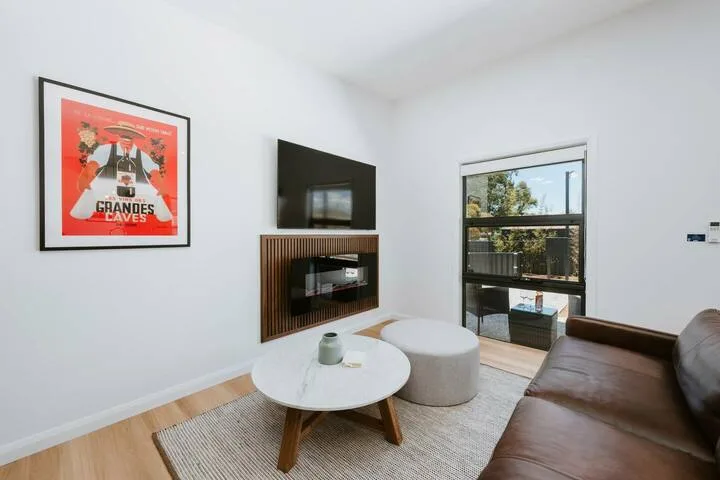 Una sala de estar con televisor, asientos y una ventana amplia.