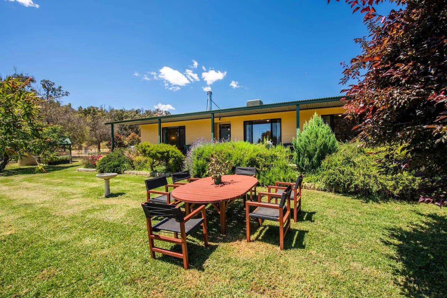 Una zona de comedor al aire libre con una mesa y asientos sobre el césped.