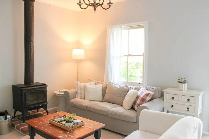 Una sala de estar con asientos acolchados, una estufa de leña y una mesa de centro.