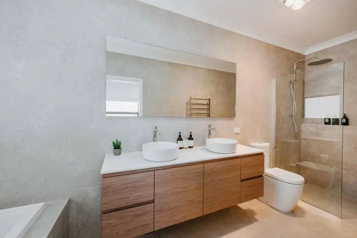 Baño moderno con un mueble de madera largo, dos lavabos y una ducha de vidrio.