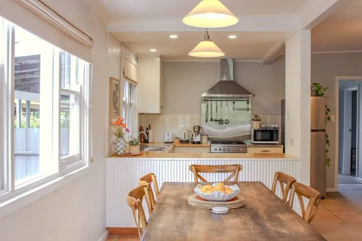 Una cocina y comedor luminosos con una mesa de madera junto a grandes ventanas.