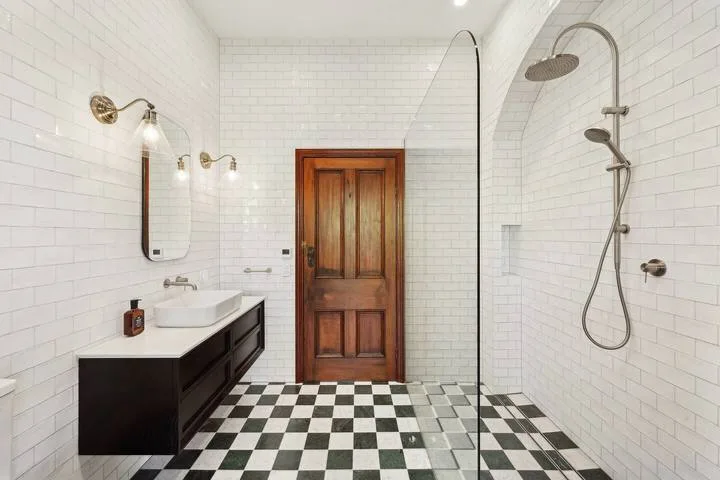 Un baño alicatado con un mueble oscuro y una ducha con mampara de vidrio.