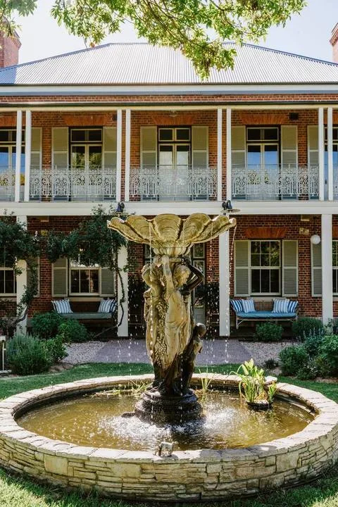 Un edificio de ladrillo con una fuente en el patio.