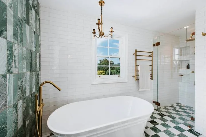 Un baño luminoso con bañera exenta, ventana y ducha de vidrio.