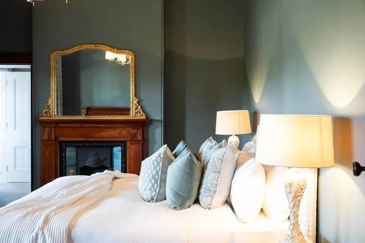 Un dormitorio con una cama arreglada, cojines decorativos y una chimenea.
