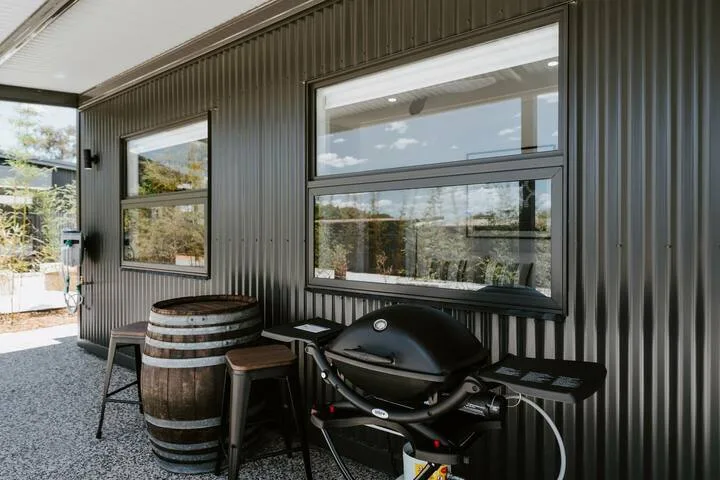 Un patio exterior cubierto con una parrilla y una mesa tipo barril.