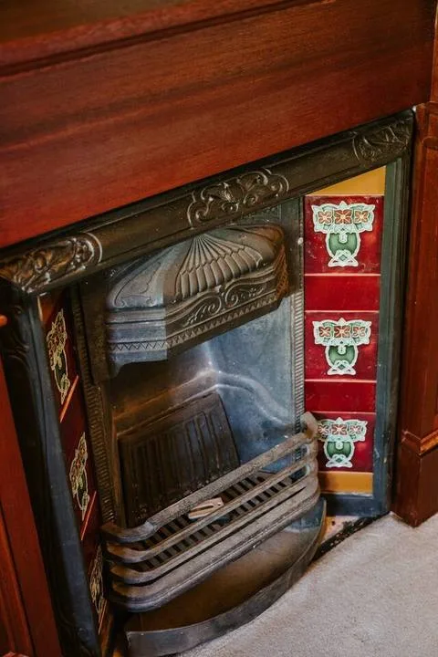 Una chimenea decorativa con una rejilla de metal oscuro en un marco de madera.