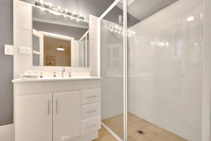 Un baño luminoso con lavabo, espejo y ducha alicatada.