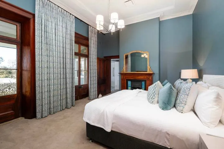 Un dormitorio con una cama grande, paredes azules y una chimenea.