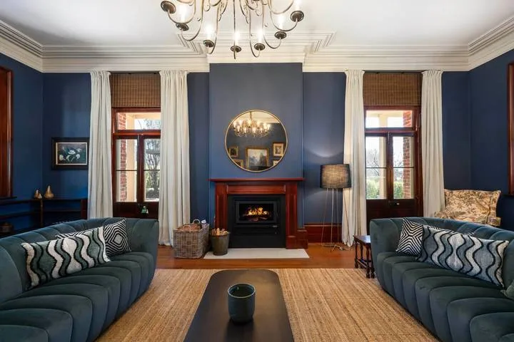 Una sala de estar con paredes azules, dos zonas para sentarse y una chimenea.