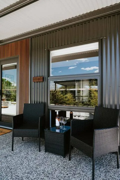 Un patio cubierto con asientos de tejido oscuro junto a grandes ventanas.