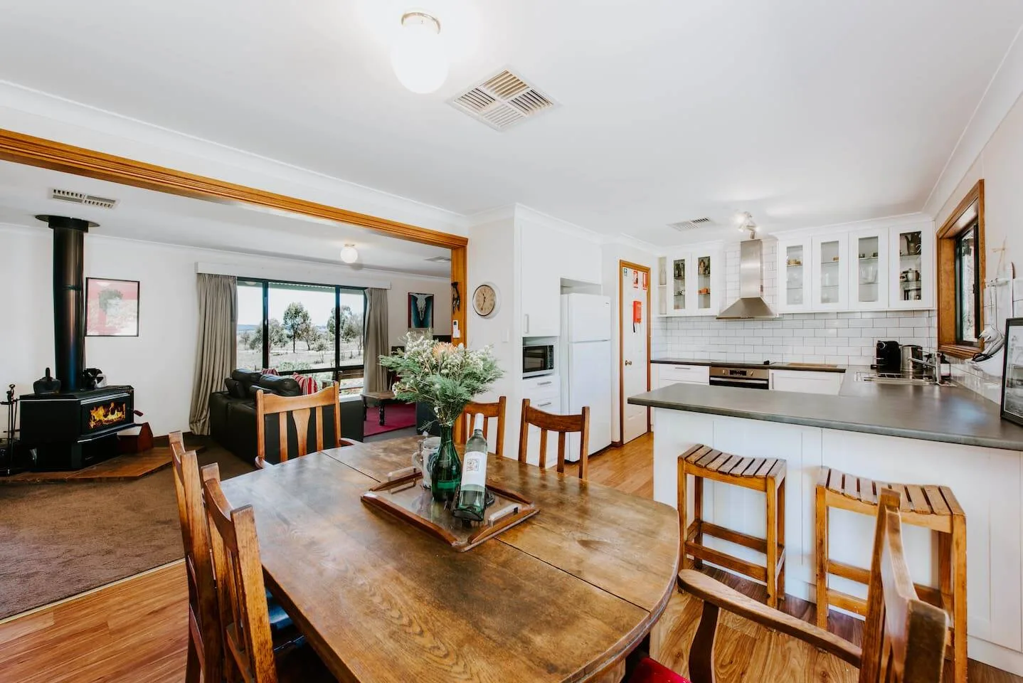 Una cocina abierta al comedor, con una mesa de madera y asientos junto a la barra.