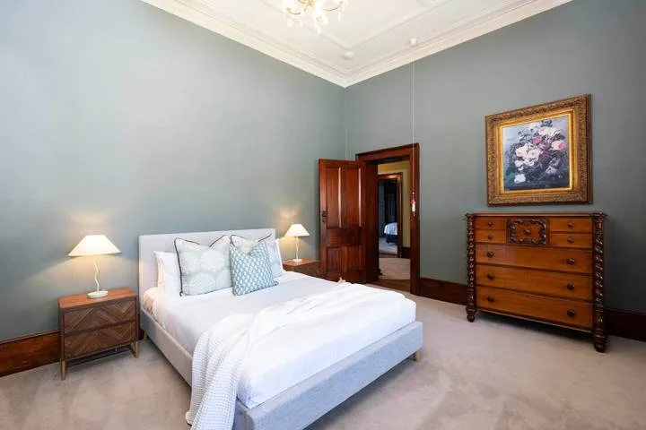 Dormitorio con una cama bien tendida, mesitas de noche y una cómoda de madera.