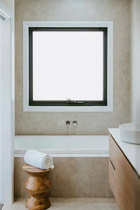 Un baño con una ventana de marco oscuro sobre la bañera.