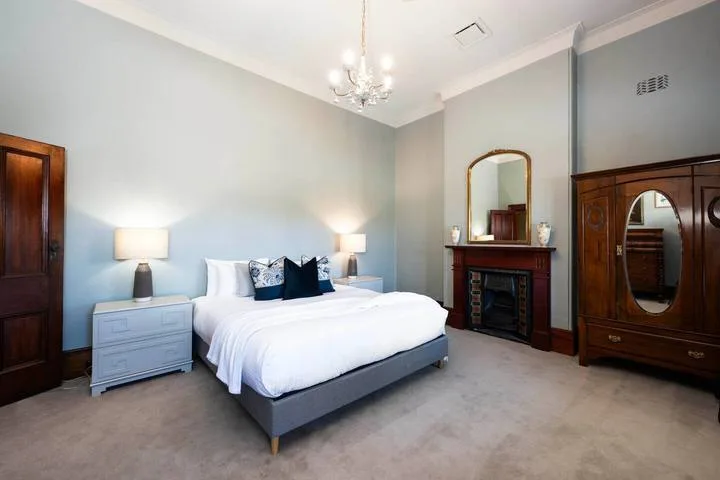 Un dormitorio con una cama bien tendida, lámparas de noche y muebles de madera oscura.