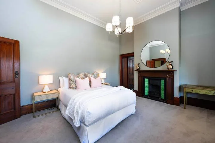 Dormitorio con una cama bien arreglada y una chimenea.