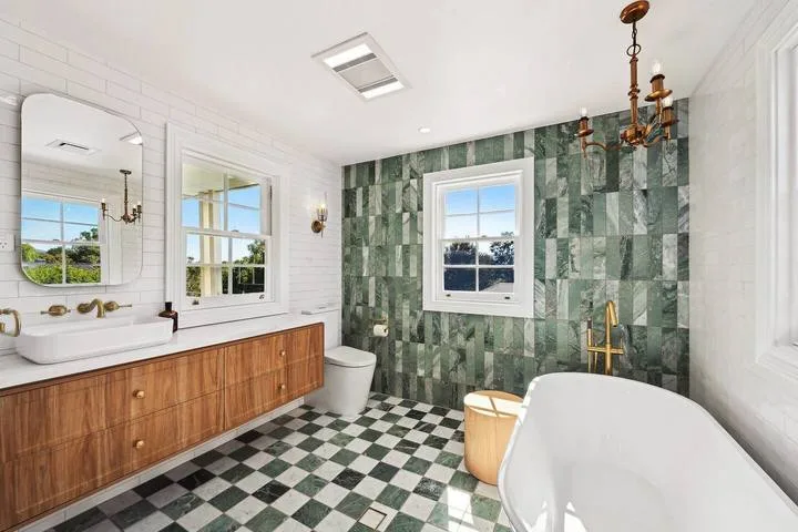 Un baño con una bañera exenta y una pared de azulejos estampados.