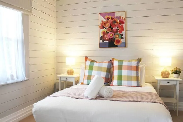 Un dormitorio luminoso con una cama bien hecha y cojines estampados de colores.