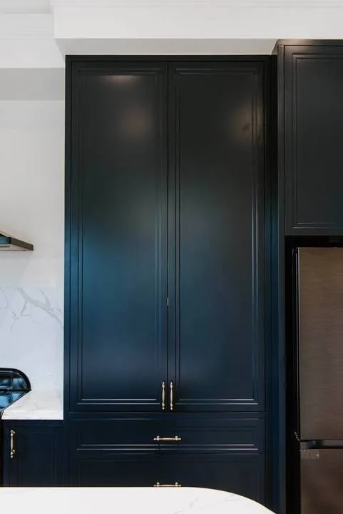 Los armarios oscuros ocupan una pared de la cocina junto a un refrigerador.