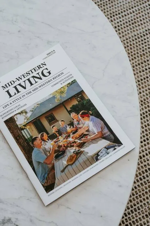 Una revista está sobre una mesa redonda junto a asientos tejidos.