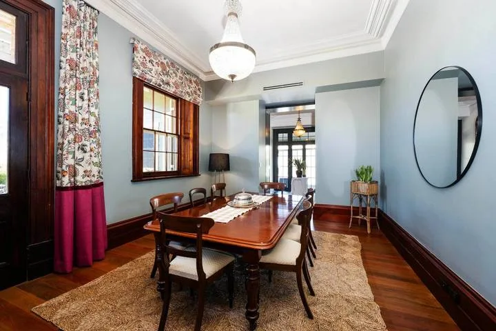 Un comedor con una mesa larga de madera, sillas y una ventana grande.