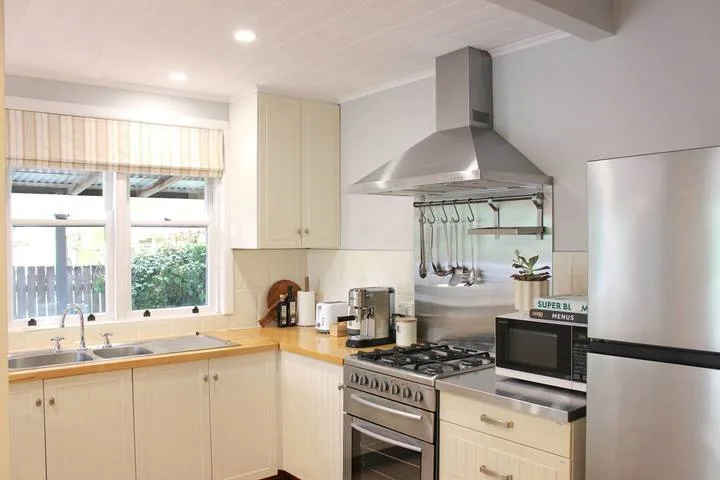 Una cocina luminosa con gabinetes claros, una estufa y una ventana grande.