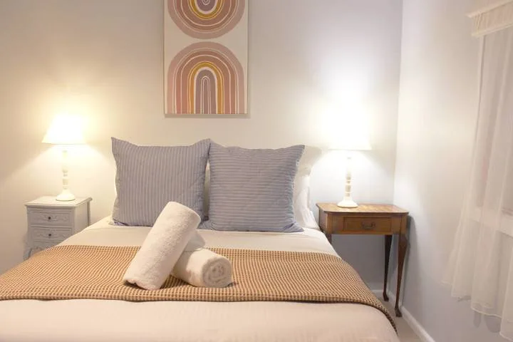 Una cama bien arreglada con almohadas a rayas y lámparas de noche.