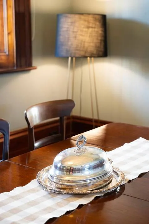 Una mesa de comedor tiene una fuente tapada debajo de una lámpara de pie.