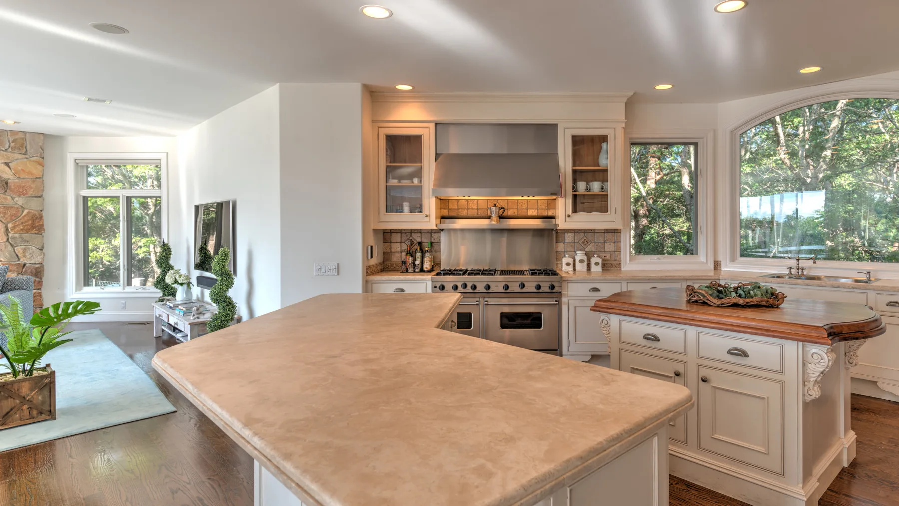 Una cocina luminosa con una isla grande y gabinetes bajo amplias ventanas.