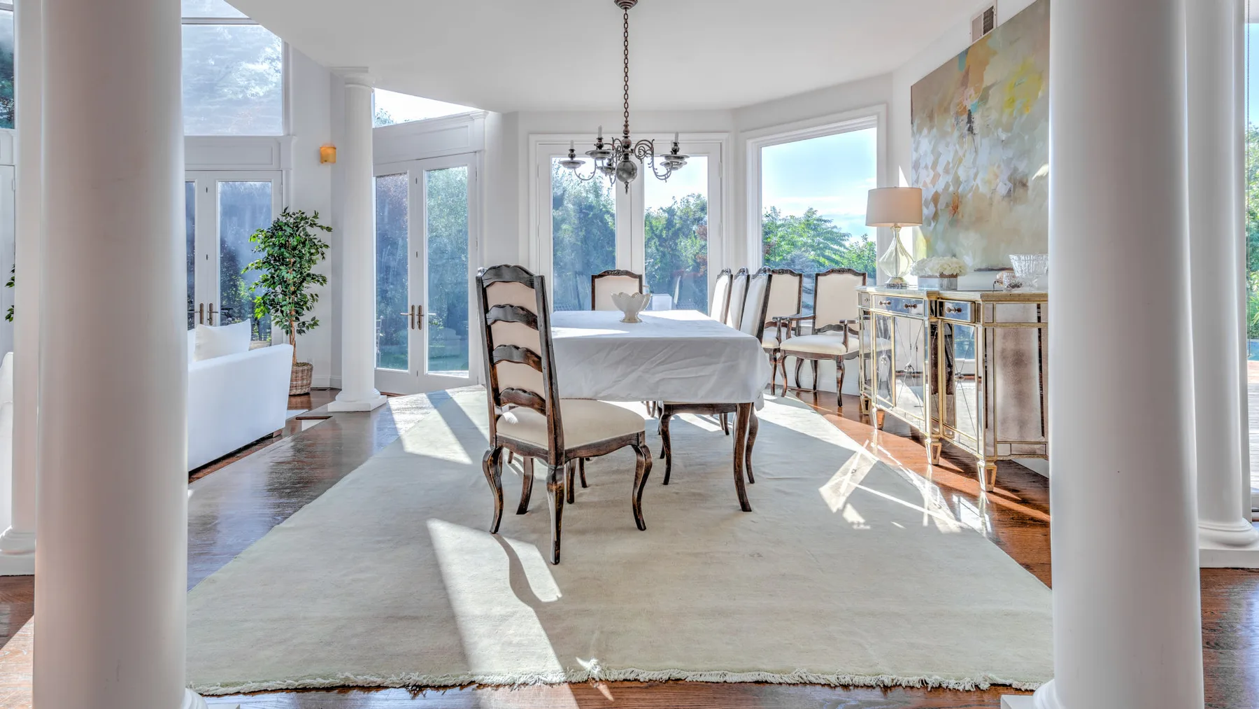 Un comedor luminoso con una mesa, sillas y grandes ventanales.