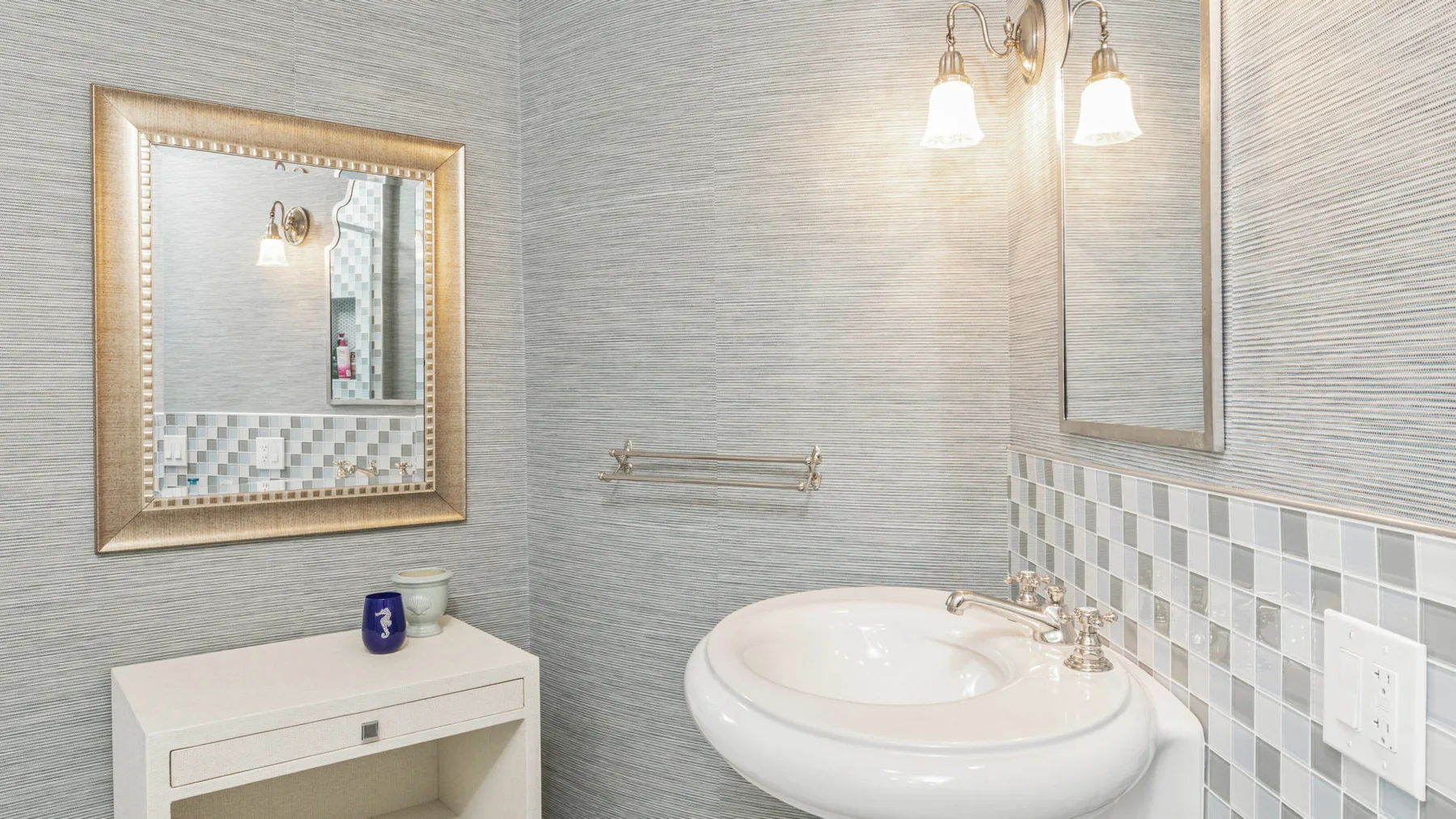 Un lavabo de baño con espejo y salpicadero de azulejos estampados.