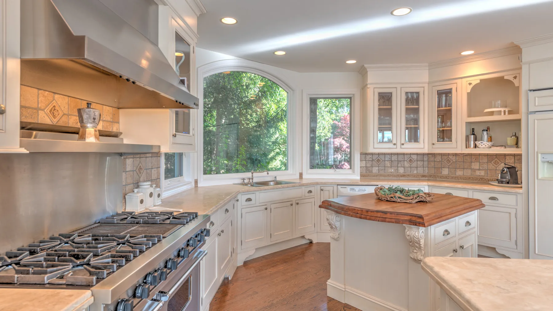 Una cocina luminosa con gabinetes blancos, una estufa amplia y una isla central.