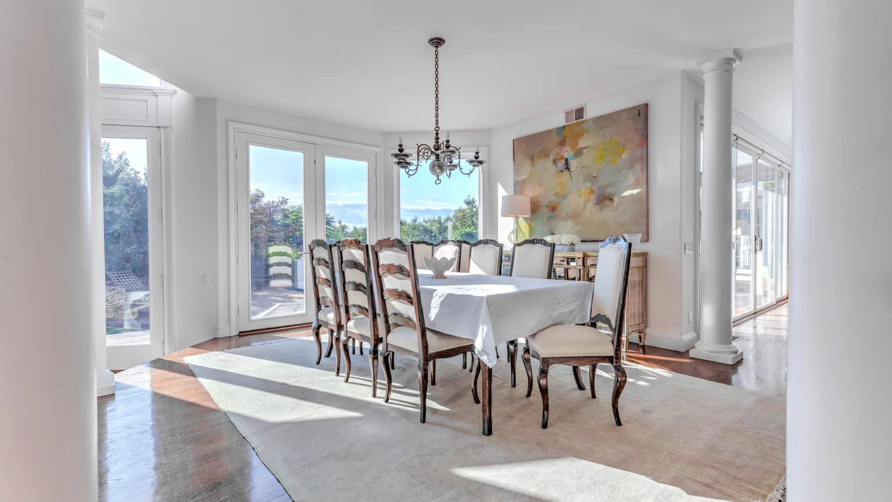 Un comedor luminoso con una mesa larga junto a grandes ventanales.