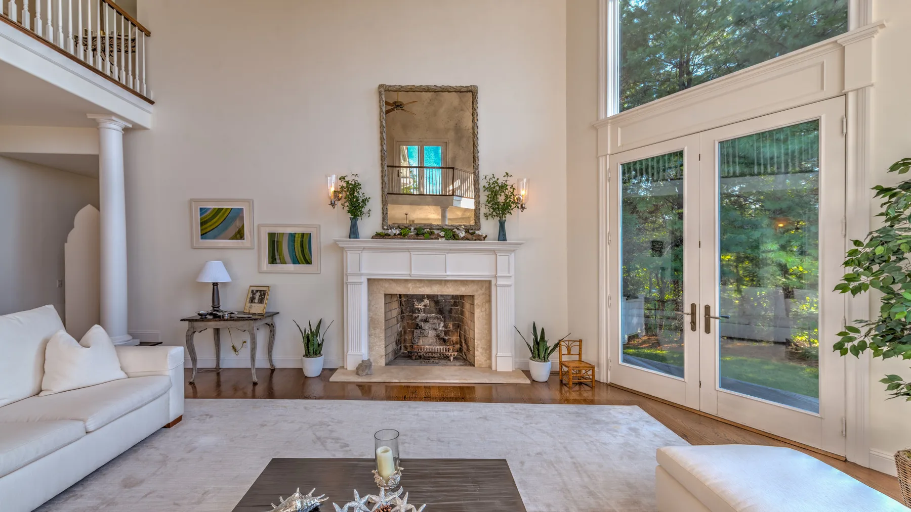 Una luminosa sala de estar con chimenea, asientos y puertas altas de vidrio.