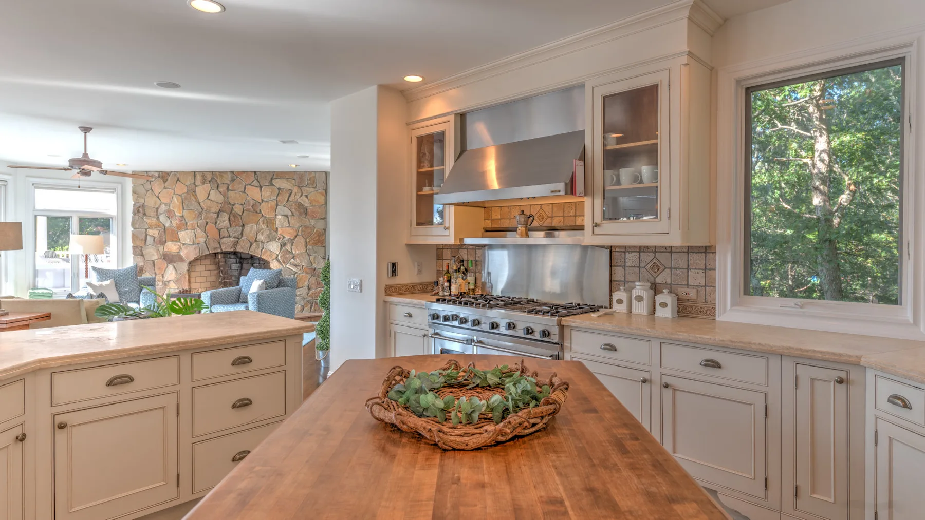 Una cocina luminosa con una isla de madera y una gran ventana con vista a los árboles.