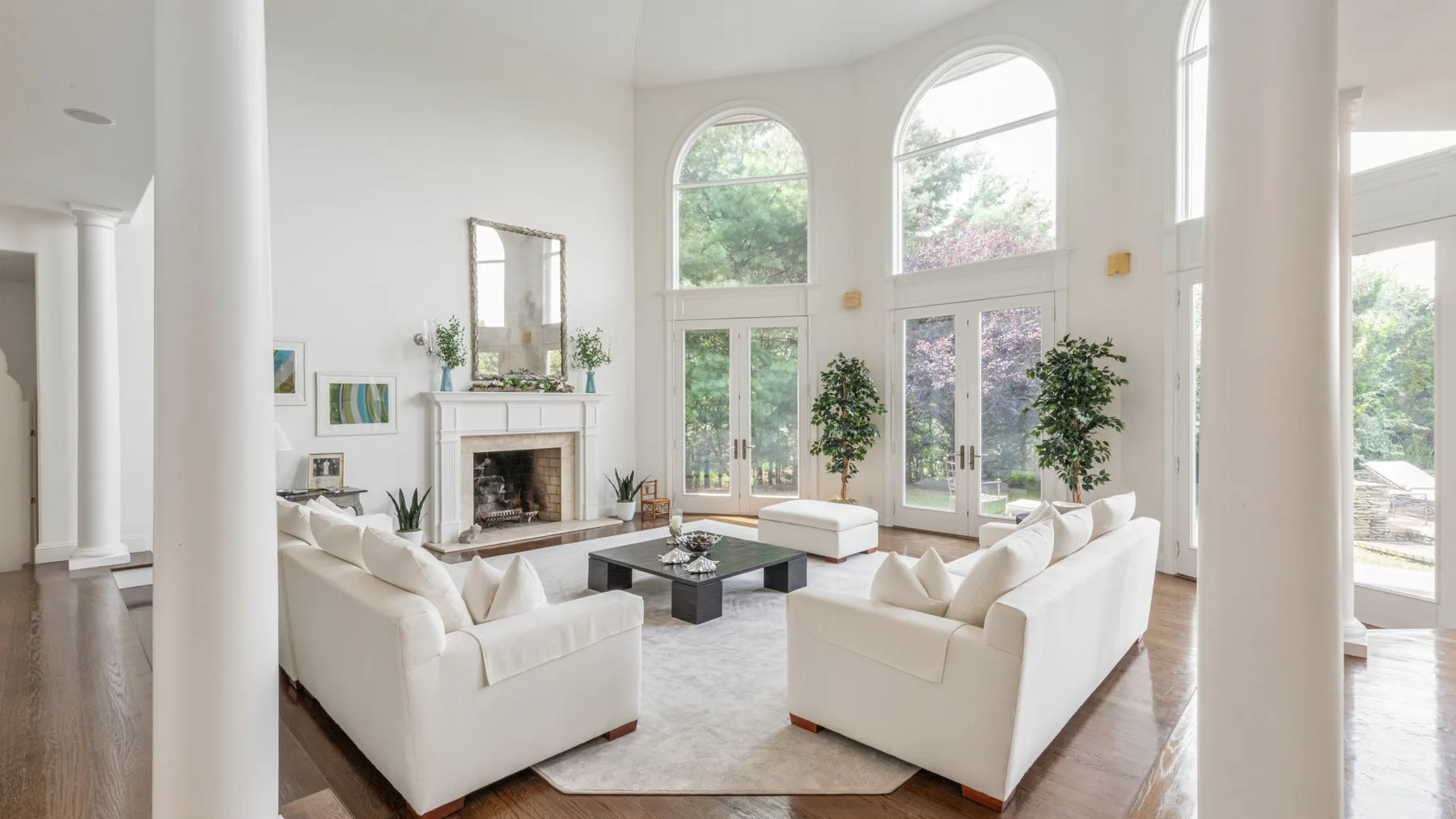 Una sala luminosa con asientos blancos, una chimenea y ventanas altas en arco.