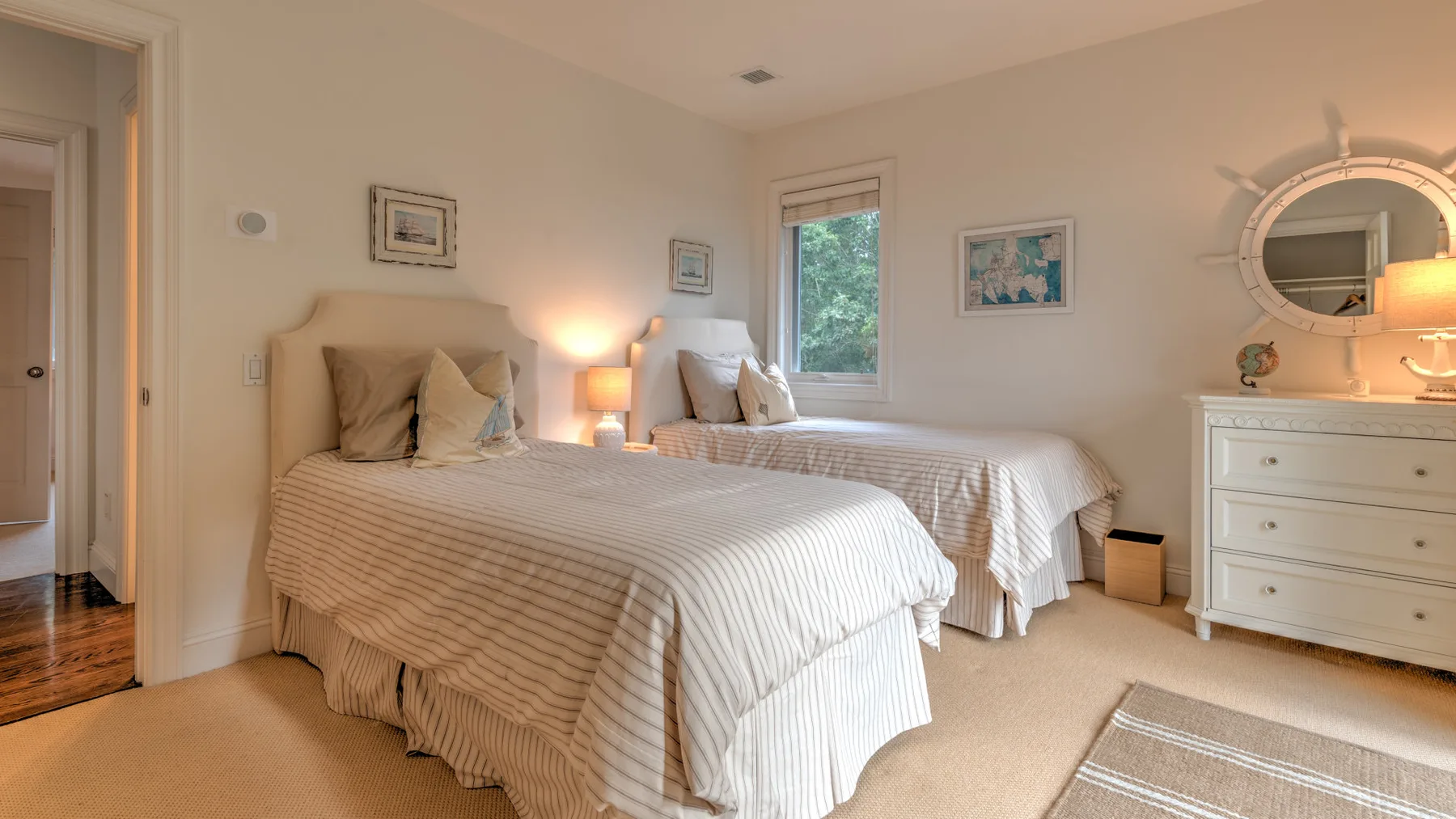 Un dormitorio luminoso con dos camas vestidas con ropa de cama clara.