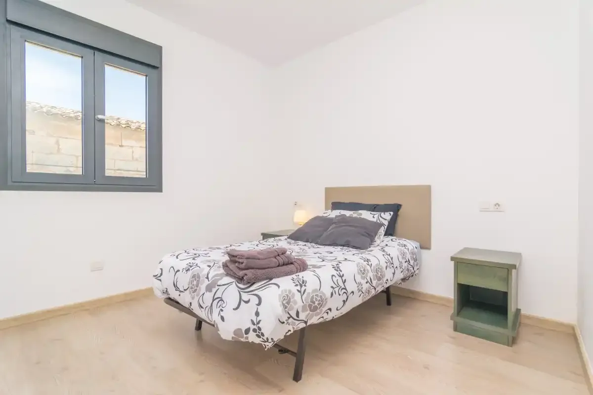 A bedroom with a bed, patterned bedding, and a window.