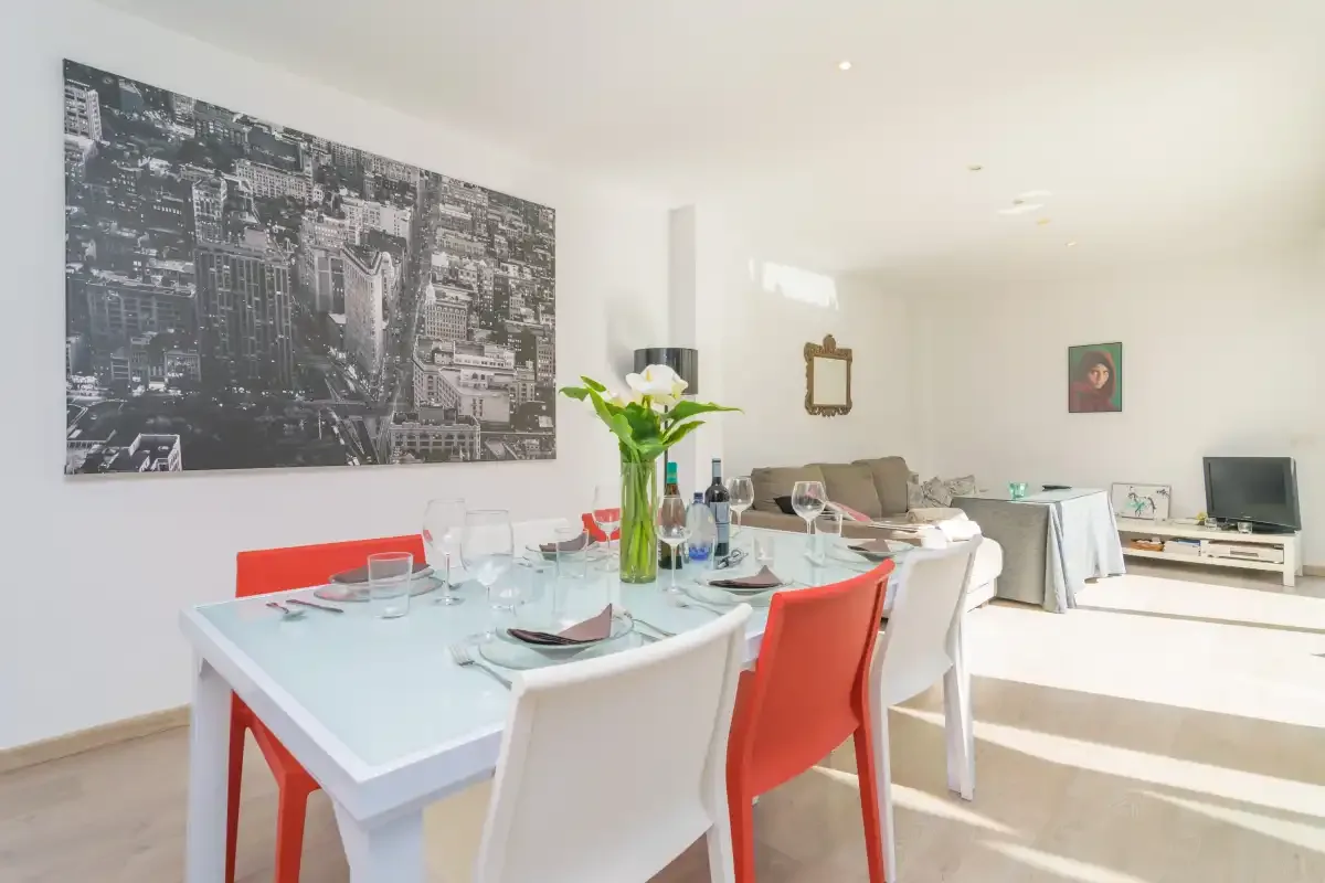 A bright dining and living area with a set table and wall art.