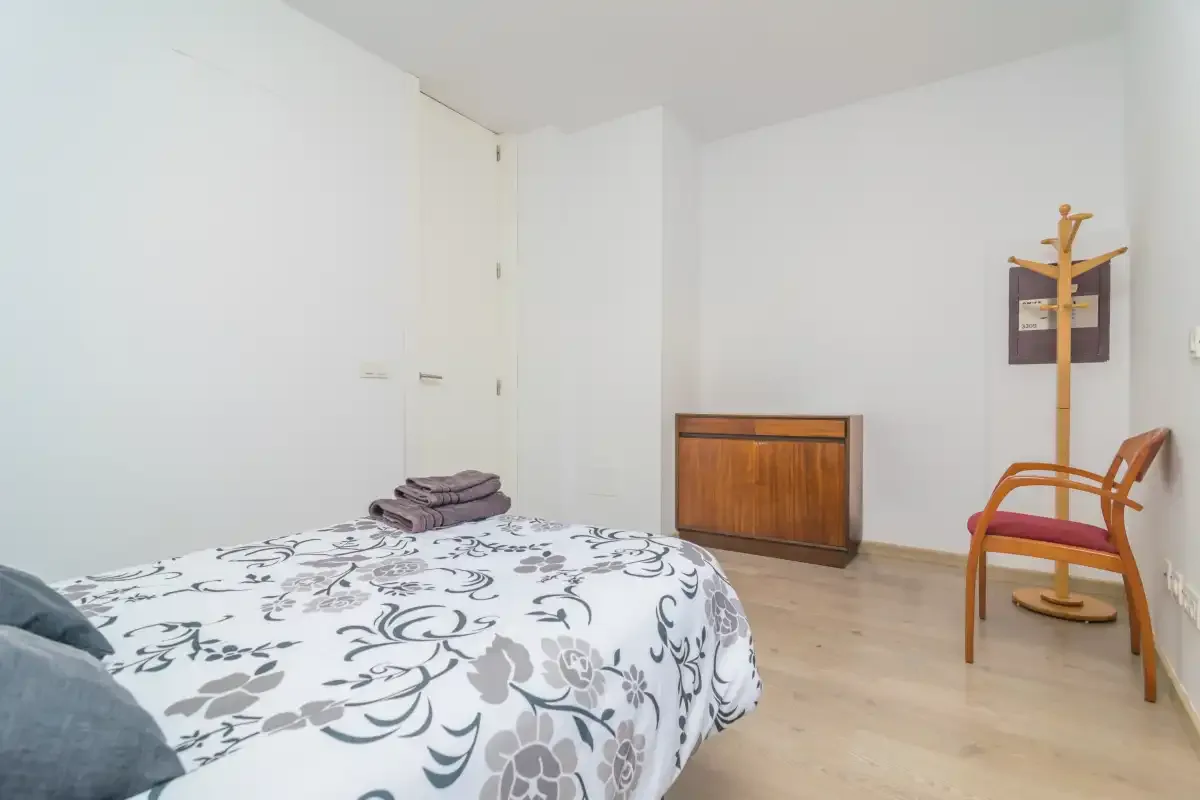 A bedroom with a floral-patterned bedspread and a wooden cabinet.